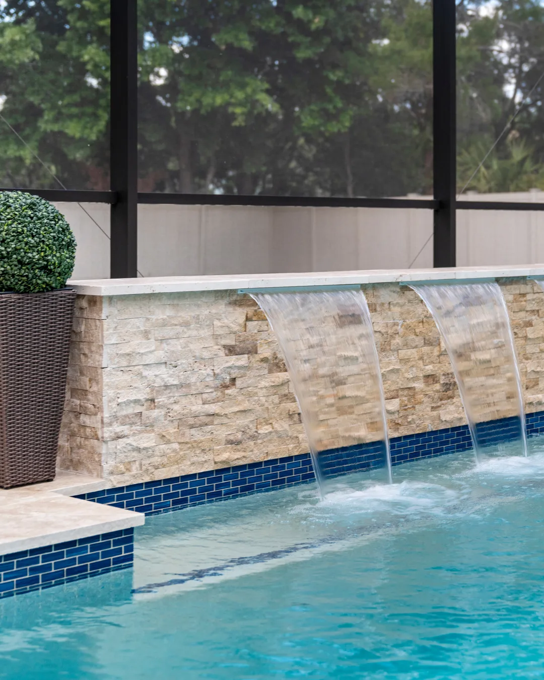 Eleven foot stacked stone water wall with three sheer descents falling into an Odessa custom pool