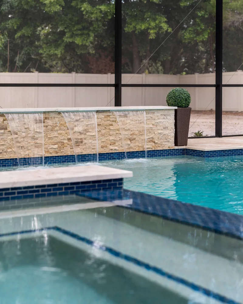 Three sheer descents falling from a stacked stone wall into a custom pool