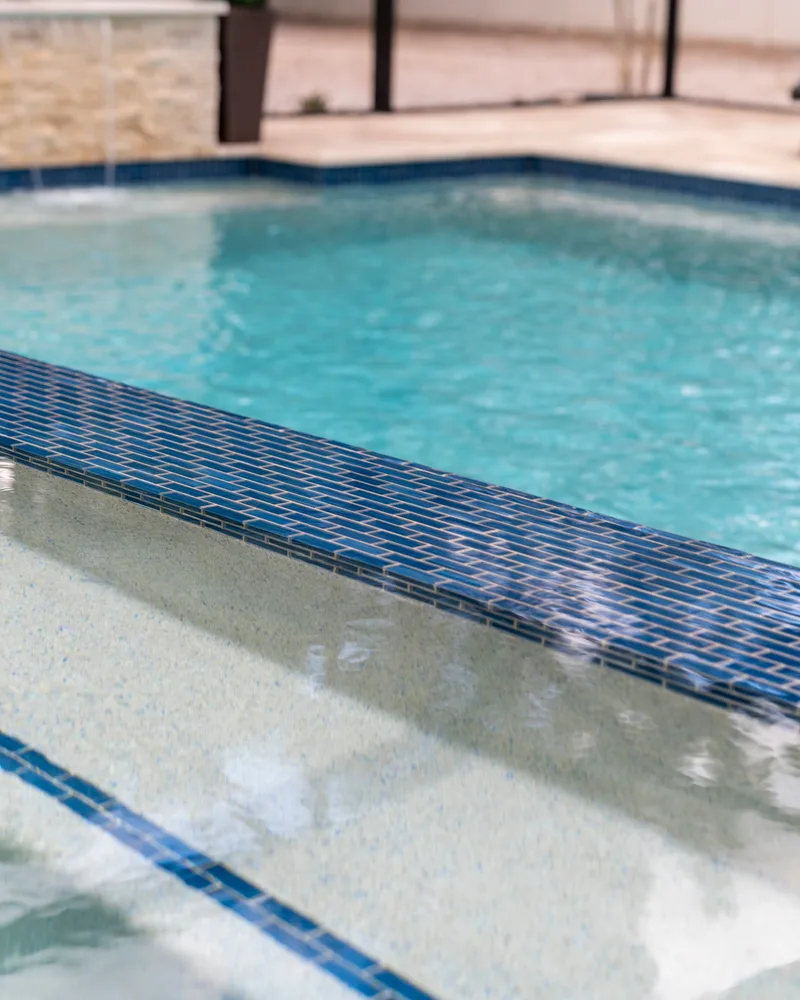 Slim blue Maretzi Cayman waterline tile along a pool step