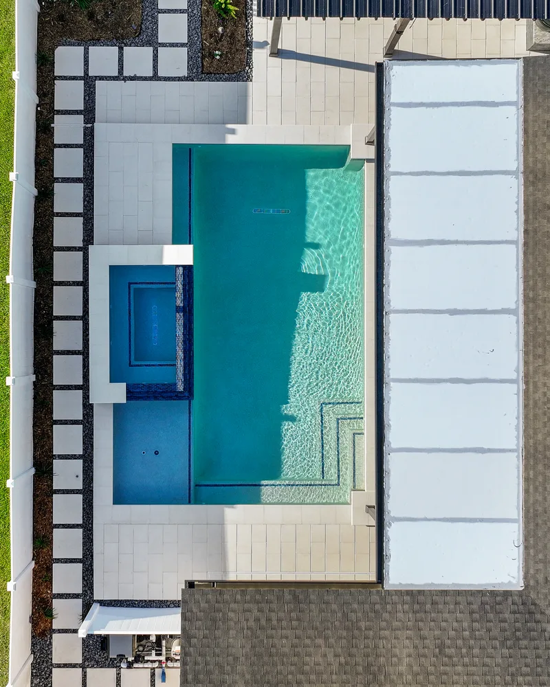 Custom pool with a water cascade and navy waterline tile built by Pool Perfection in Seminole