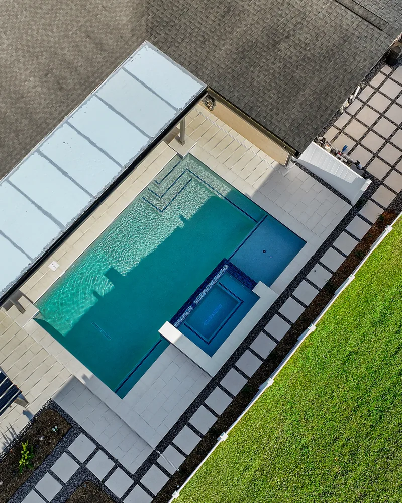 Custom pool with a water cascade and navy waterline tile built by Pool Perfection in Seminole