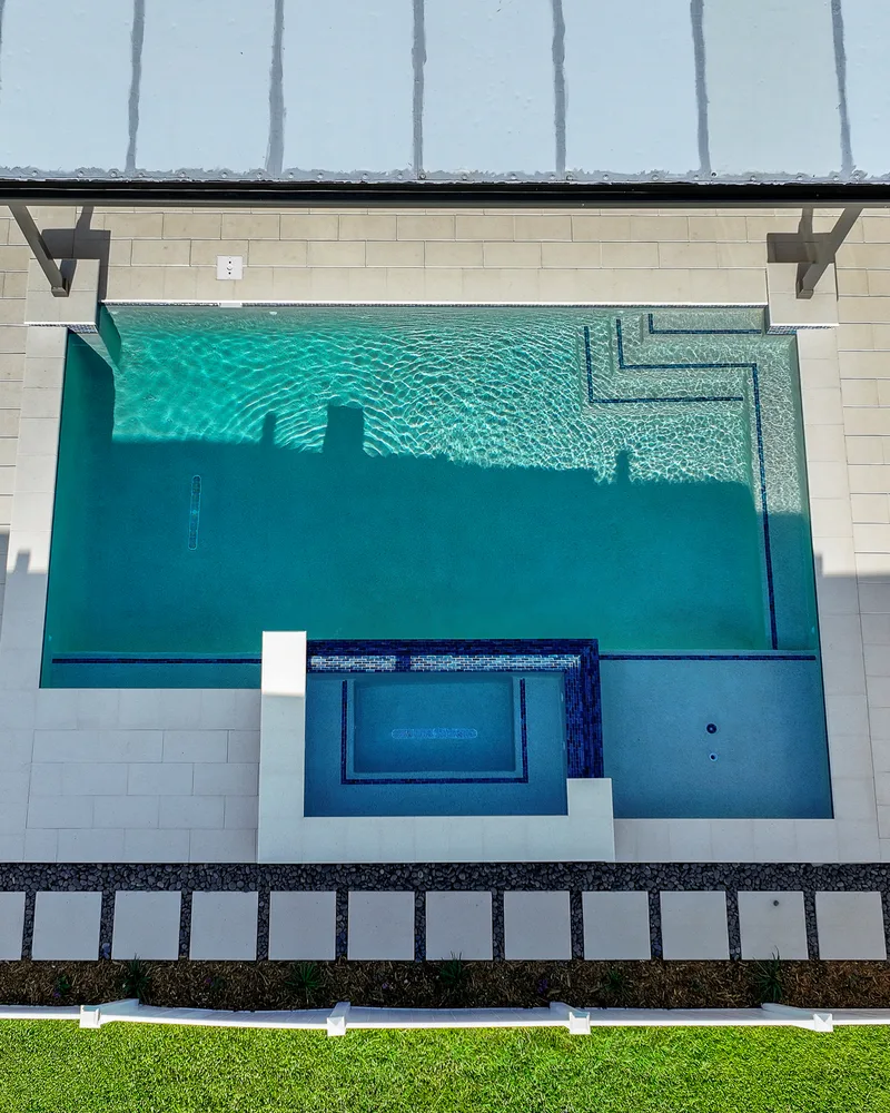 Custom pool with a water cascade and navy waterline tile built by Pool Perfection in Seminole