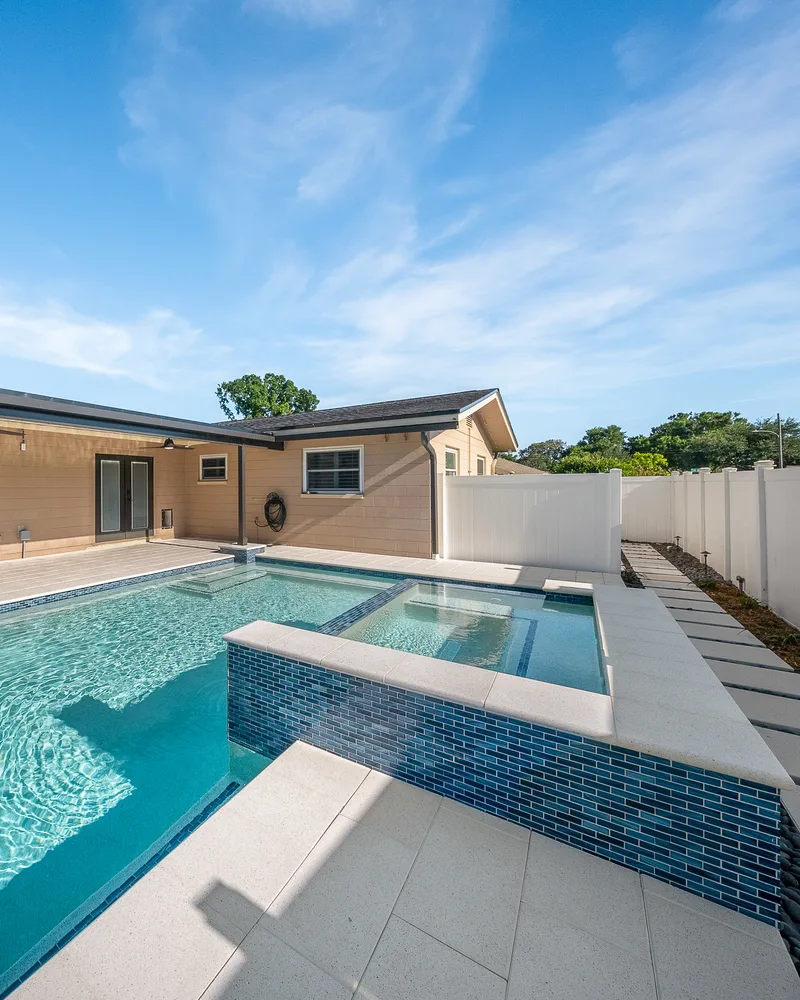 Custom pool with a water cascade and navy waterline tile built by Pool Perfection in Seminole