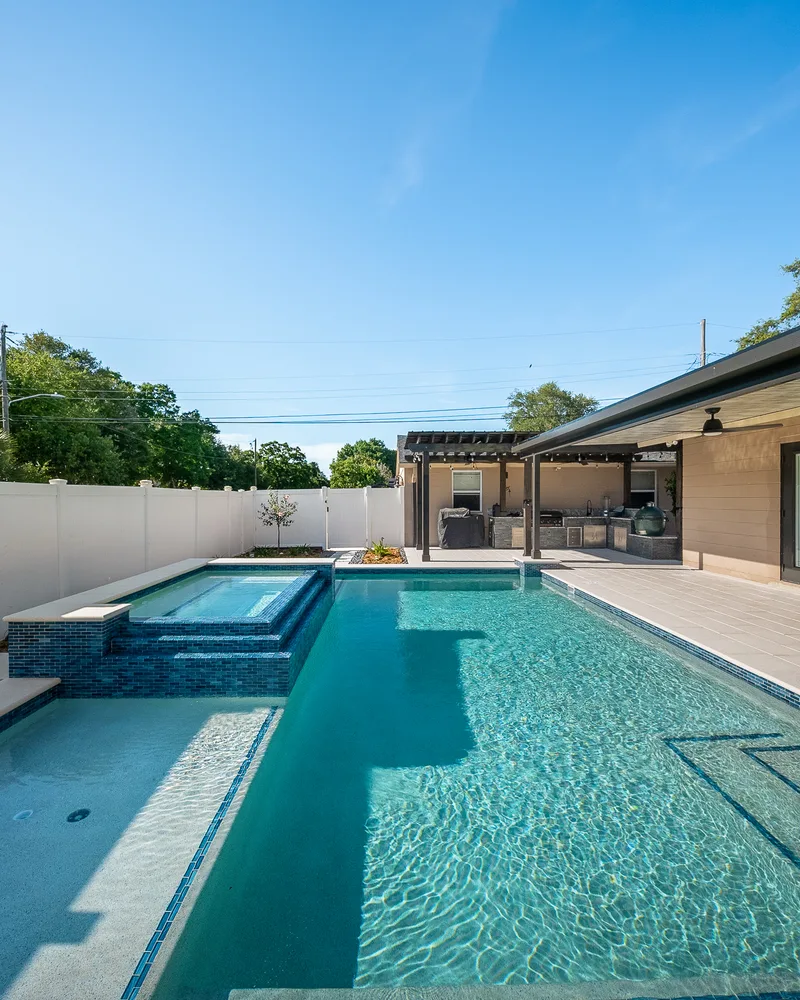 Custom pool with a water cascade and navy waterline tile built by Pool Perfection in Seminole