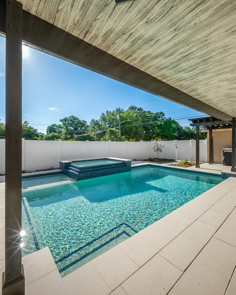 Custom pool with a water cascade and navy waterline tile built by Pool Perfection in Seminole