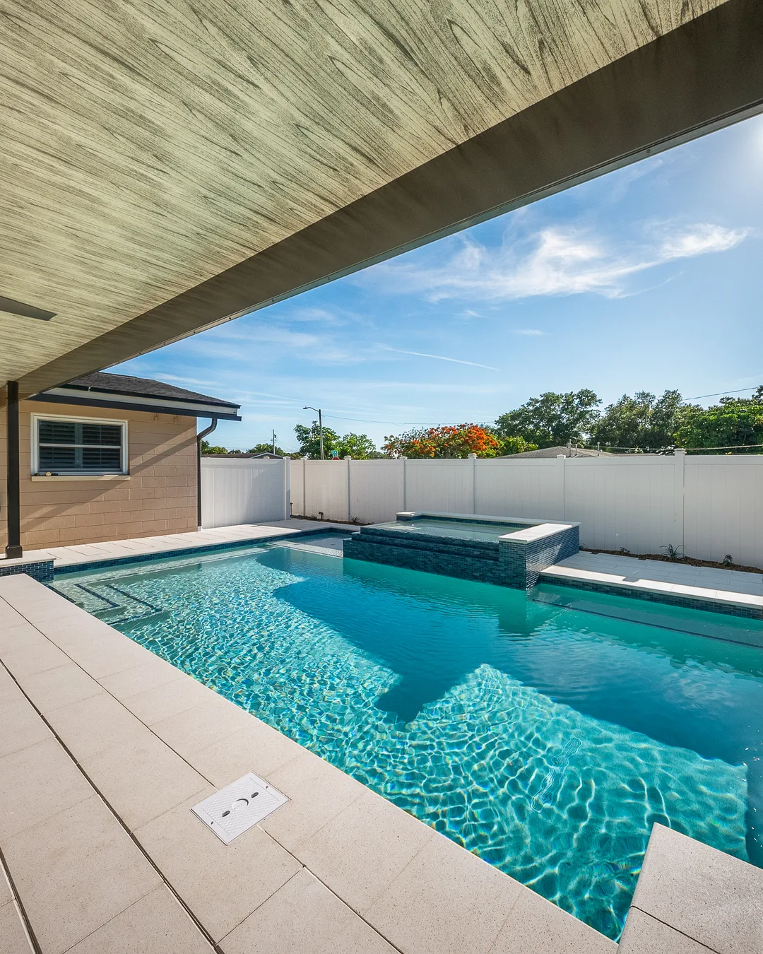 Wide view of a Seminole custom pool with navy glass waterline tile and ivory shell stone coping