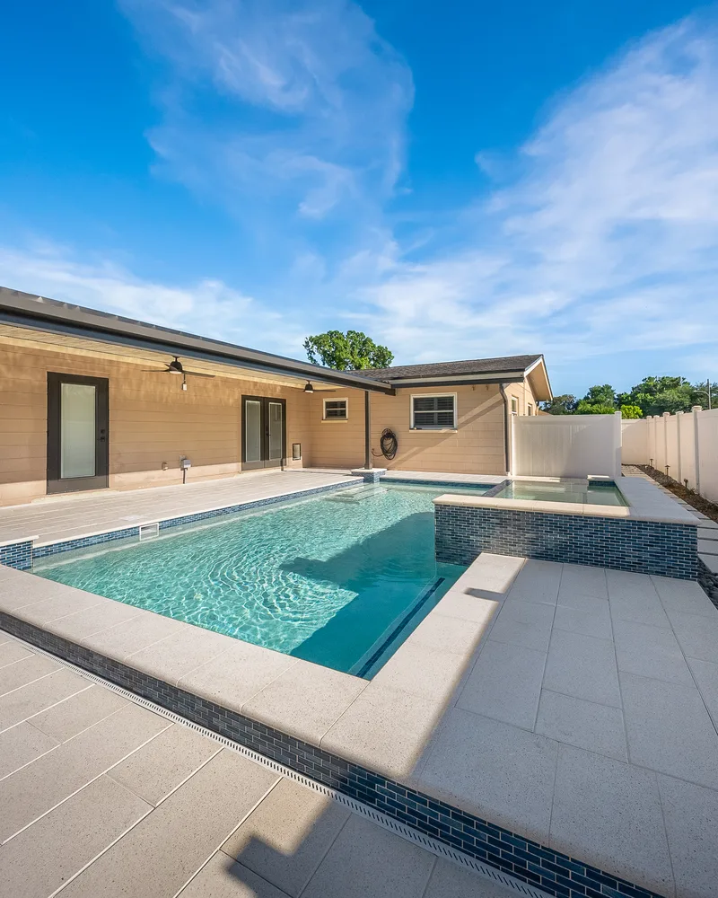 Custom pool with a water cascade and navy waterline tile built by Pool Perfection in Seminole