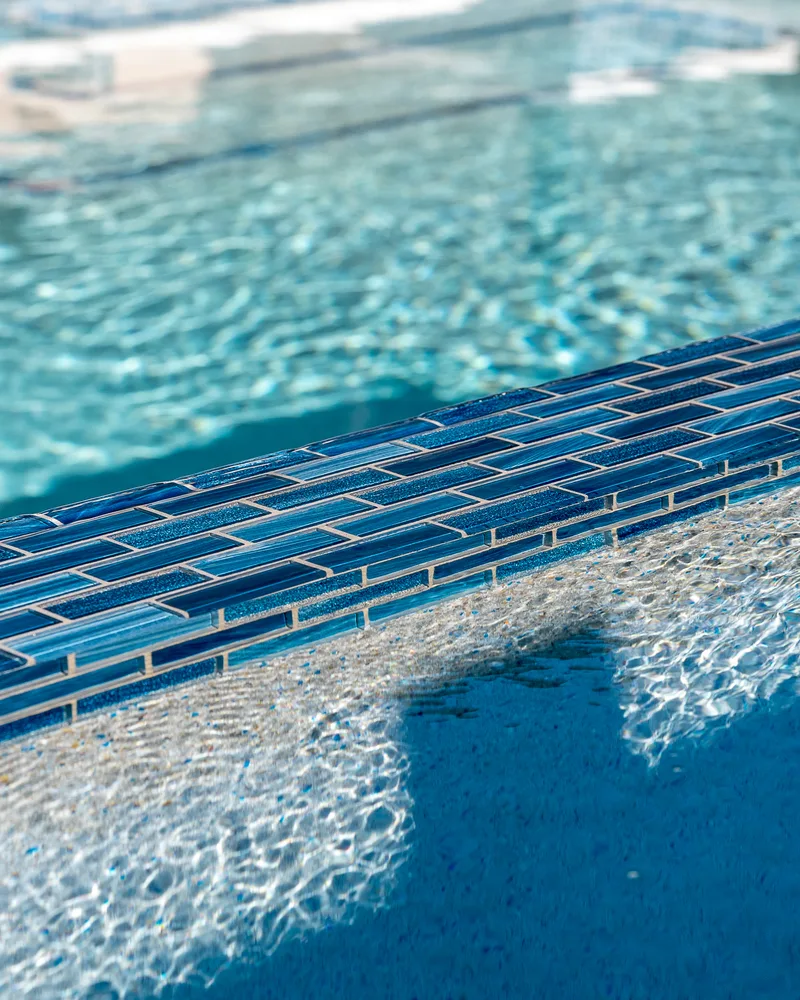 Custom pool with a water cascade and navy waterline tile built by Pool Perfection in Seminole