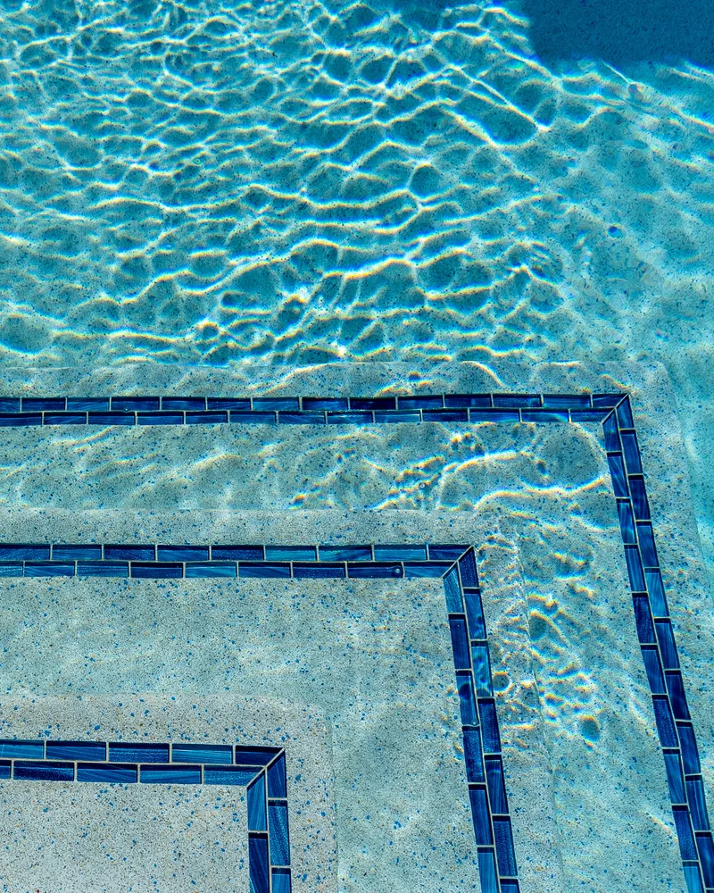 Custom pool with a water cascade and navy waterline tile built by Pool Perfection in Seminole