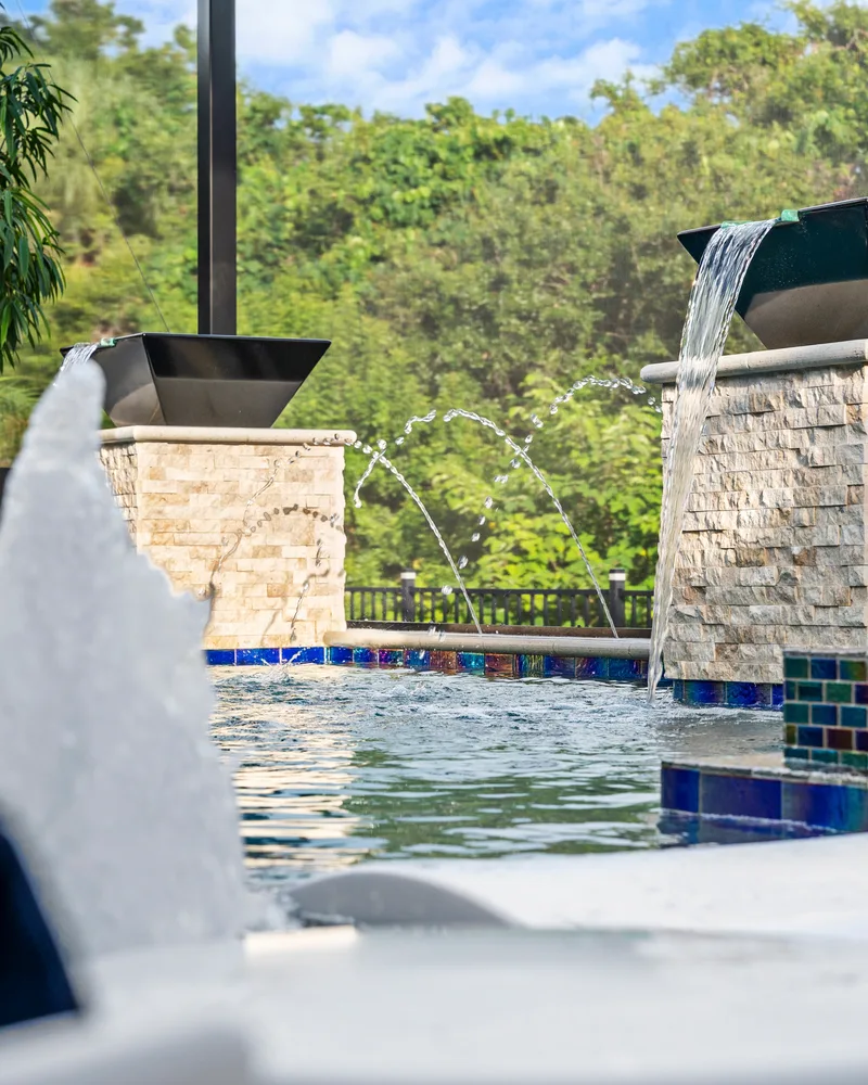 Two stacked stone pillars topped with black water bowls spilling into a custom pool