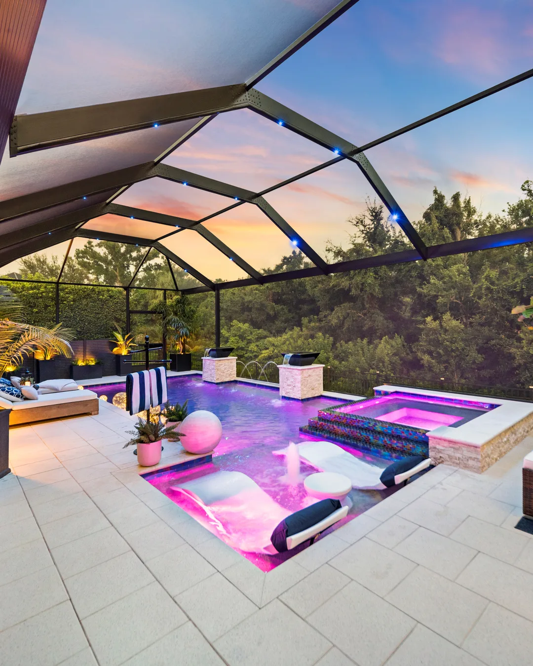Tampa custom pool and spa glowing at sunset with stone pillars and a lit lounge area