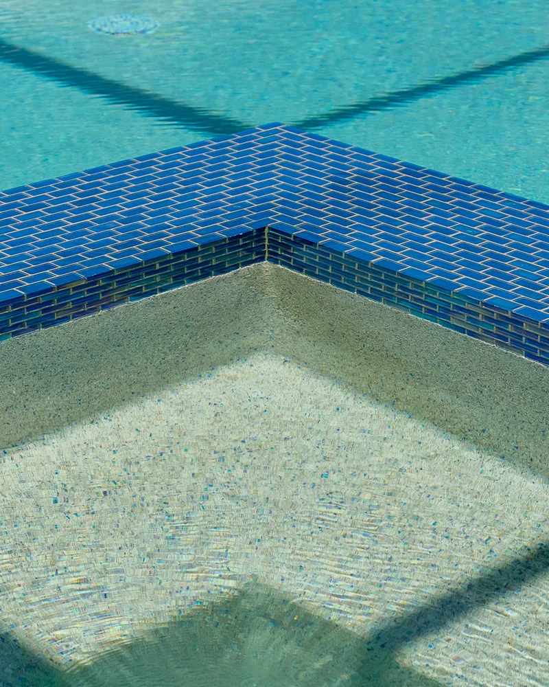 Custom pool and raised spa with Blue Lagoon glass tile built by Pool Perfection in Wesley Chapel