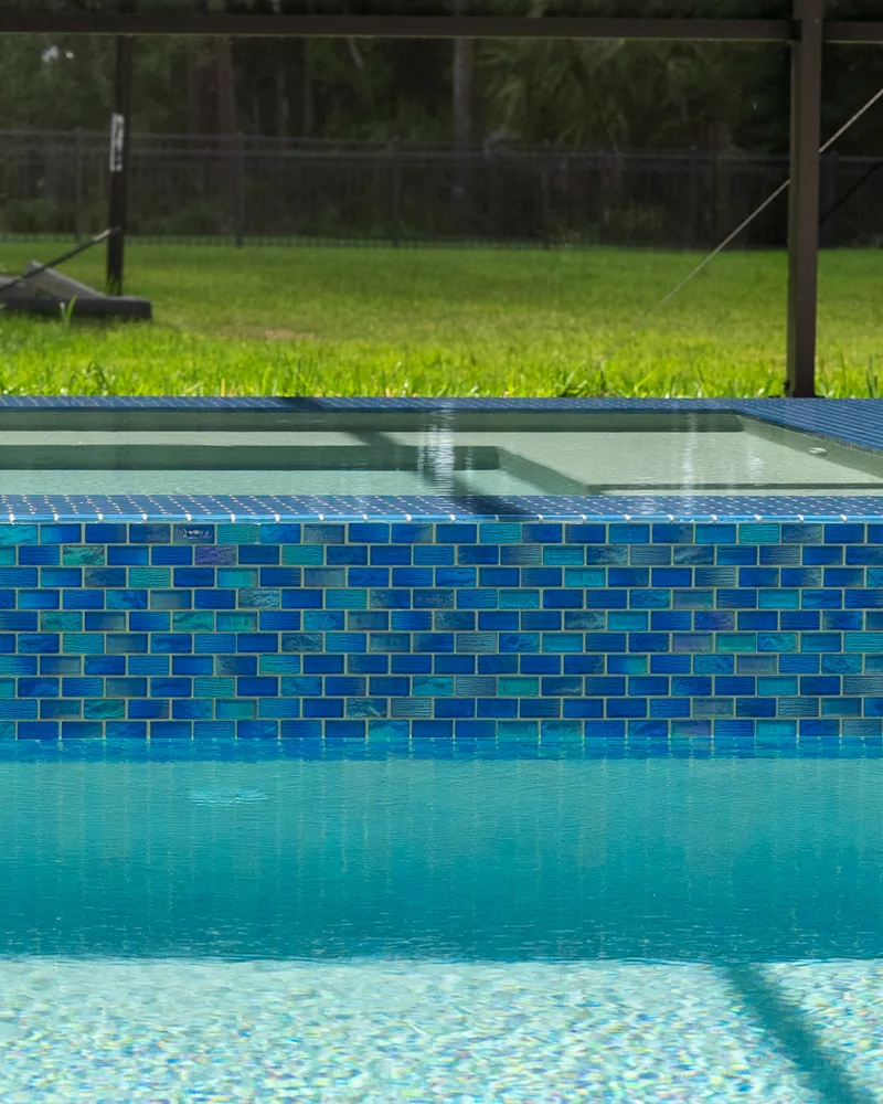 Custom pool and raised spa with Blue Lagoon glass tile built by Pool Perfection in Wesley Chapel