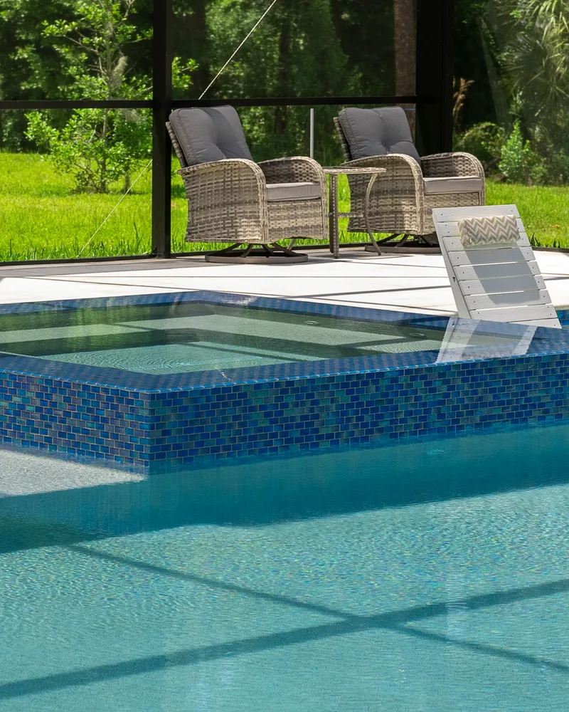 Custom pool and raised spa with Blue Lagoon glass tile built by Pool Perfection in Wesley Chapel