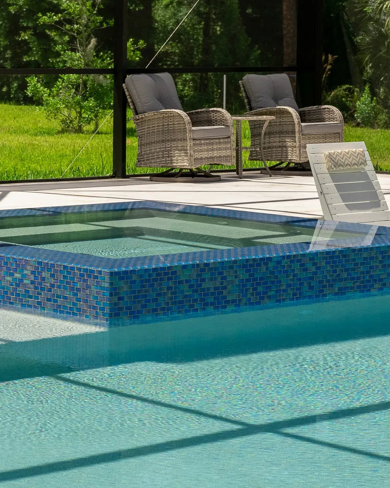 Custom pool and raised spa with Blue Lagoon glass tile built by Pool Perfection in Wesley Chapel