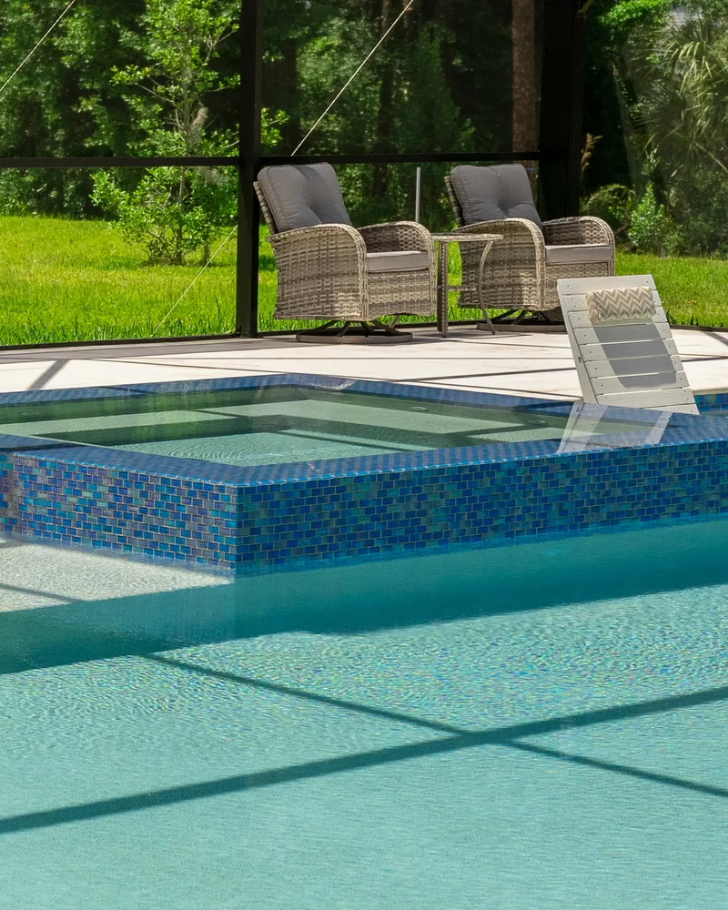 Custom pool and raised spa with Blue Lagoon glass tile built by Pool Perfection in Wesley Chapel