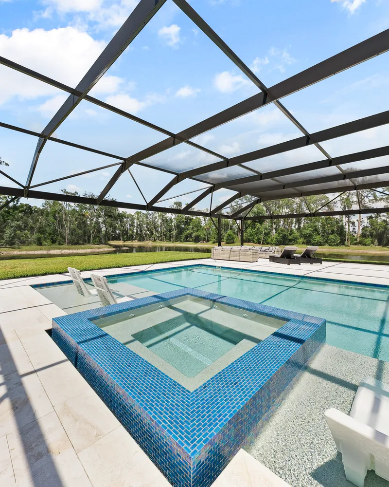 Custom pool and raised spa with Blue Lagoon glass tile built by Pool Perfection in Wesley Chapel